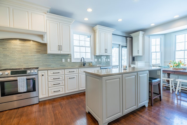 kitchen with white cabinets, a kitchen island, stainless steel gas stove, sink, and dark hardwood / wood-style floors