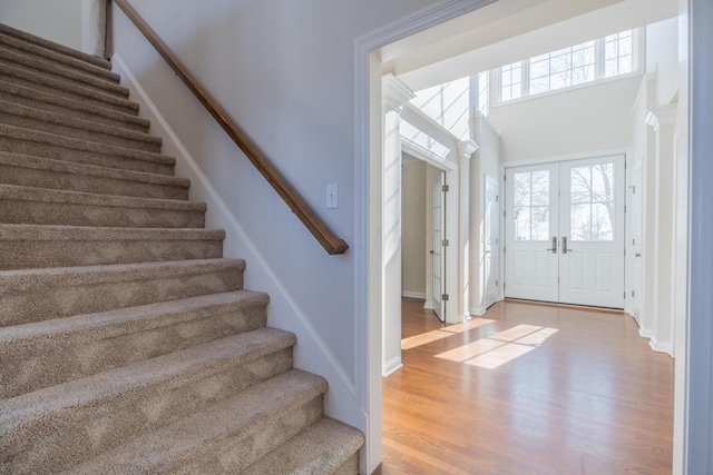 foyer featuring light hardwood / wood-style floors, a high ceiling, and french doors