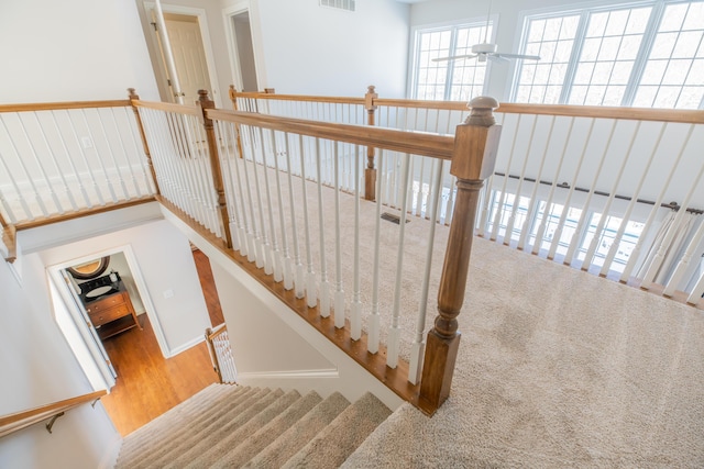 stairs with hardwood / wood-style floors and ceiling fan