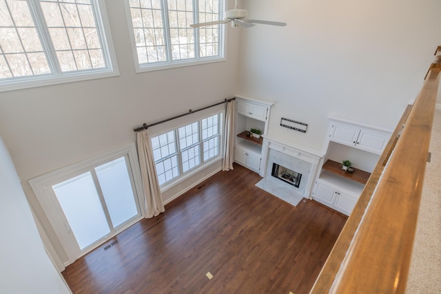 unfurnished living room with dark hardwood / wood-style flooring, plenty of natural light, a high end fireplace, and ceiling fan