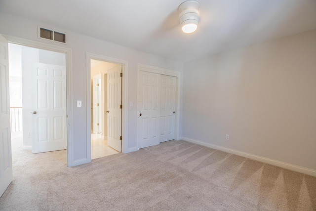 unfurnished bedroom with light carpet and a closet