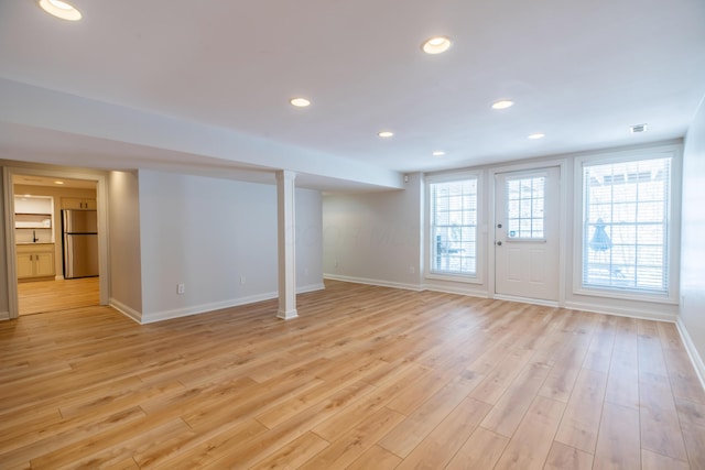 basement with light wood-type flooring and stainless steel fridge