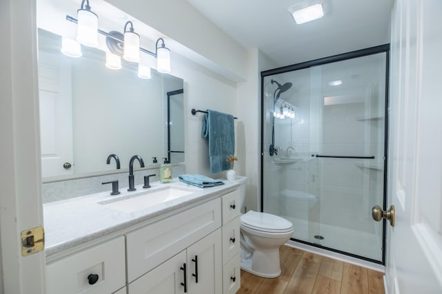 bathroom featuring toilet, walk in shower, hardwood / wood-style floors, and vanity