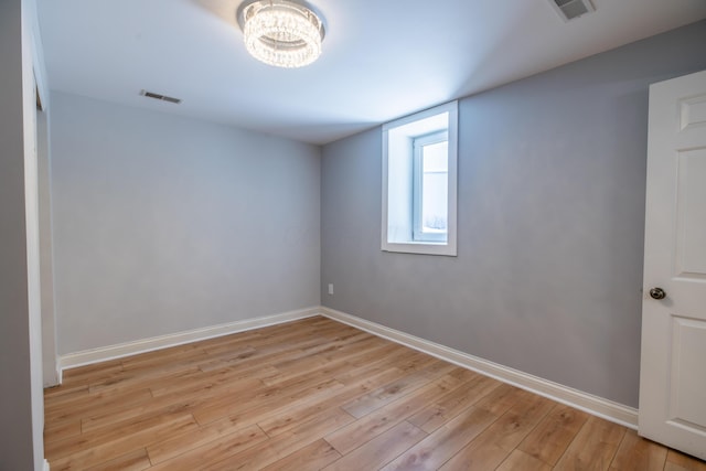 unfurnished room with light wood-type flooring and a chandelier