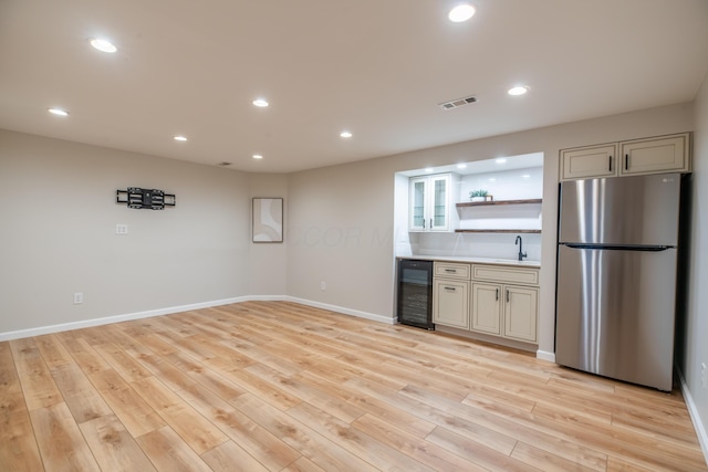 kitchen featuring stainless steel refrigerator, light wood-type flooring, sink, and beverage cooler