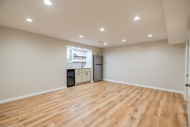 spare room featuring sink, light wood-type flooring, and beverage cooler