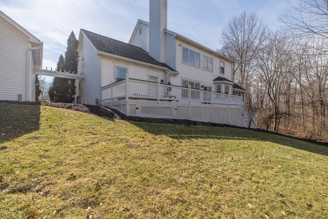 back of property with a deck, a pergola, and a lawn