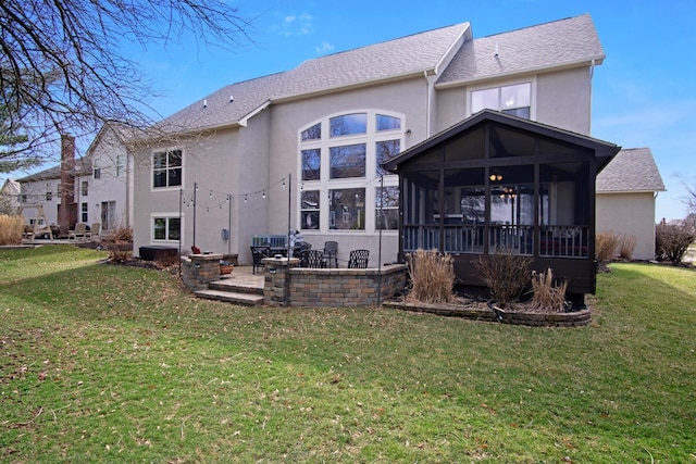 6268 Bellow Valley Dr, Dublin, OH 43016 - rear view of house featuring a sunroom, a shingled roof, stucco siding, a patio area, and a lawn