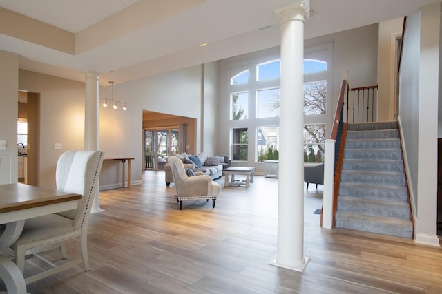 6268 Bellow Valley Dr, Dublin, OH 43016 - living area featuring baseboards, light wood-style floors, a towering ceiling, and ornate columns
