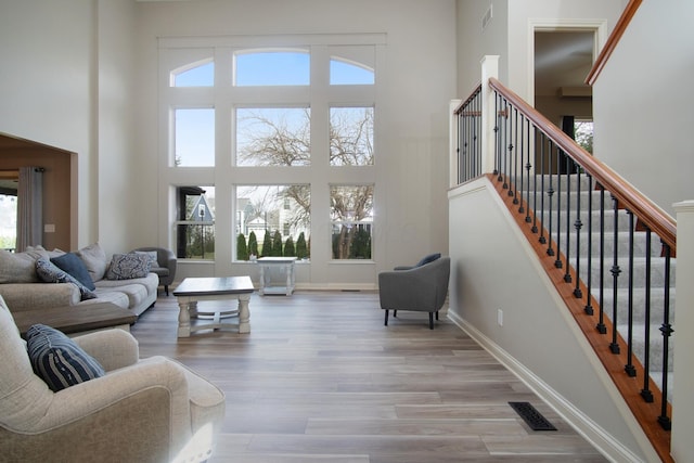 6268 Bellow Valley Dr, Dublin, OH 43016 - living room featuring visible vents, wood finished floors, baseboards, a towering ceiling, and stairs