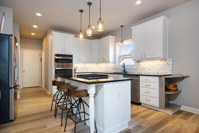 6268 Bellow Valley Dr, Dublin, OH 43016 - kitchen featuring light wood-style flooring, appliances with stainless steel finishes, white cabinetry, dark countertops, and a kitchen breakfast bar