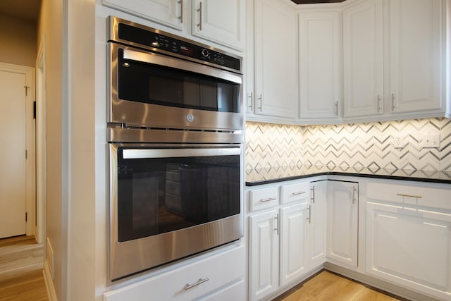 6268 Bellow Valley Dr, Dublin, OH 43016 - kitchen with stainless steel double oven, light wood-style flooring, dark countertops, and white cabinets