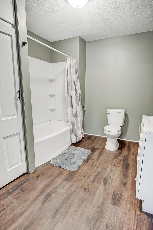 bathroom with hardwood / wood-style floors, a textured ceiling, and shower / bath combo with shower curtain