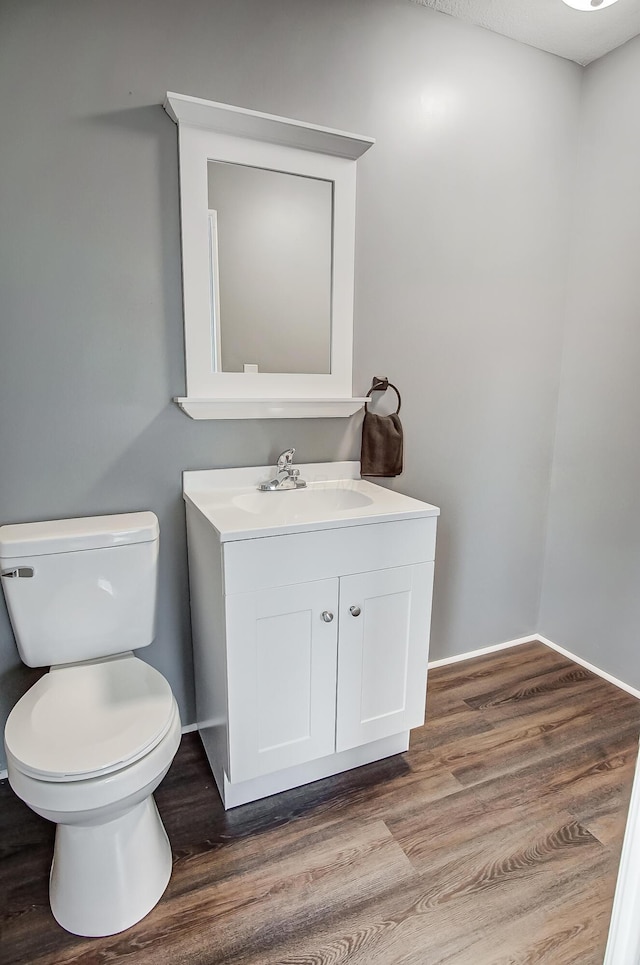 bathroom with wood-type flooring, vanity, and toilet