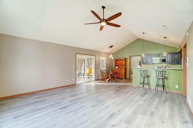 unfurnished living room with lofted ceiling, ceiling fan, and light wood-type flooring