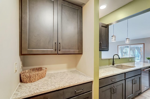 kitchen with dark brown cabinetry, sink, decorative light fixtures, dishwasher, and light stone countertops