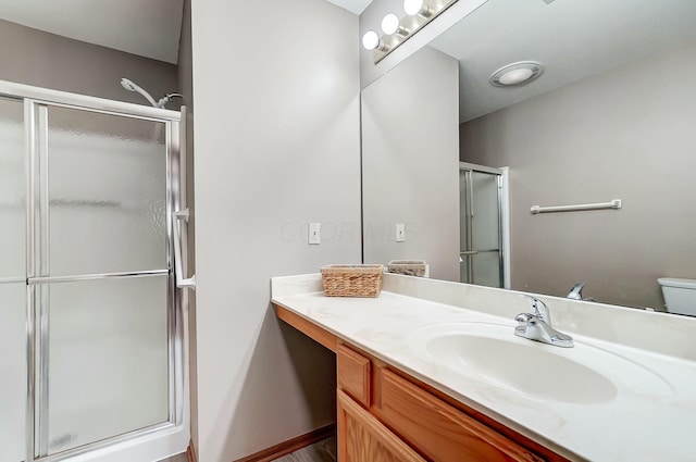 bathroom featuring vanity, a shower with shower door, and toilet