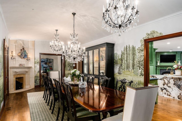 dining area with an inviting chandelier, hardwood / wood-style flooring, a high end fireplace, and ornamental molding