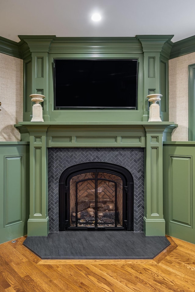 room details with wood-type flooring, ornamental molding, and a fireplace