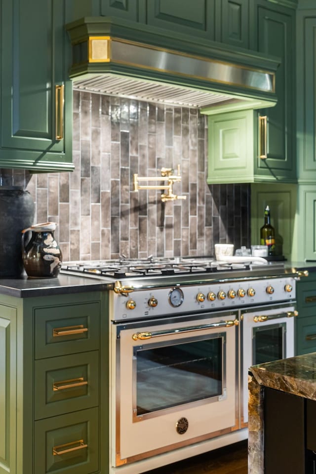 kitchen with double oven range, custom range hood, backsplash, and green cabinetry