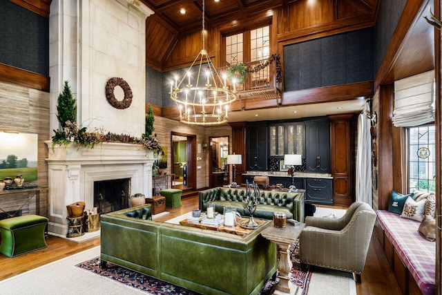 living room featuring a towering ceiling, coffered ceiling, a notable chandelier, beamed ceiling, and light wood-type flooring