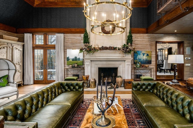 living room with a towering ceiling, a chandelier, and french doors