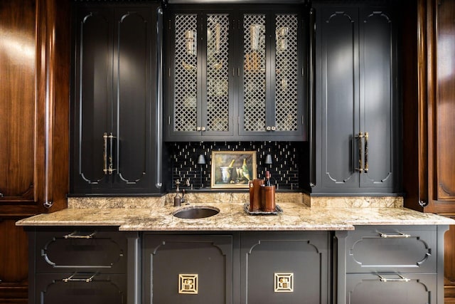 bar featuring tasteful backsplash, sink, and light stone counters