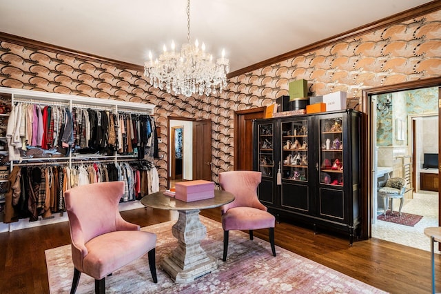 living area with hardwood / wood-style flooring, ornamental molding, and a notable chandelier