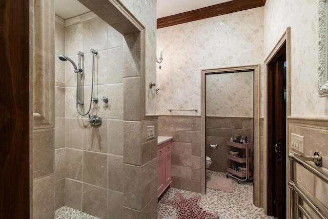 bathroom with toilet, tile walls, a tile shower, ornamental molding, and vanity