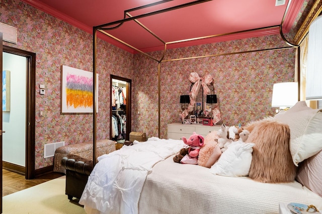 bedroom with ornamental molding, a spacious closet, hardwood / wood-style floors, and a closet