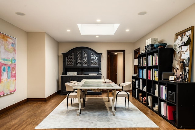 dining area with wood-type flooring, sink, and a skylight