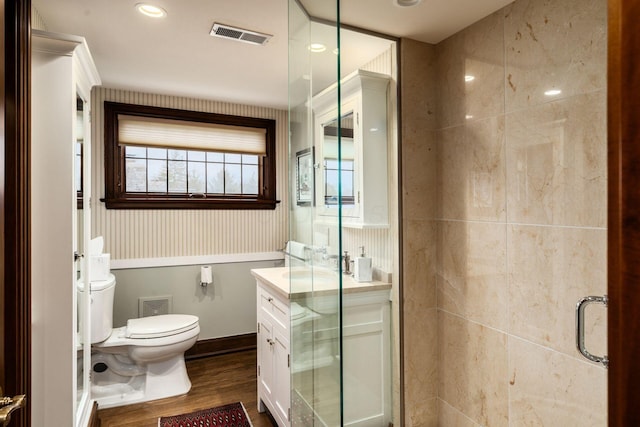 bathroom with hardwood / wood-style flooring, vanity, toilet, and a shower with shower door