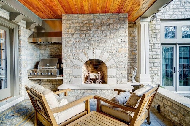 interior space with ornate columns, a stone fireplace, french doors, and wooden ceiling