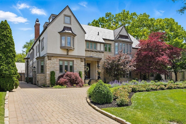 2528 Tremont Rd, Columbus, OH 43221 - tudor-style house featuring stucco siding, stone siding, a chimney, a front yard, and driveway
