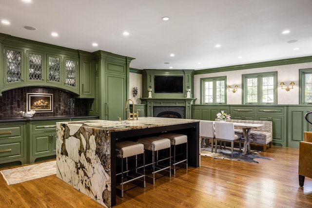 2528 Tremont Rd, Columbus, OH 43221 - kitchen with green cabinetry, a fireplace, a decorative wall, a breakfast bar area, and an island with sink