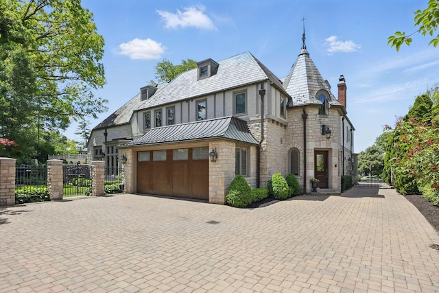 2528 Tremont Rd, Columbus, OH 43221 - tudor-style house featuring a high end roof, a standing seam roof, decorative driveway, stone siding, and a gate