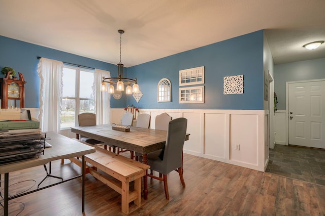 dining space featuring dark wood-type flooring and a notable chandelier