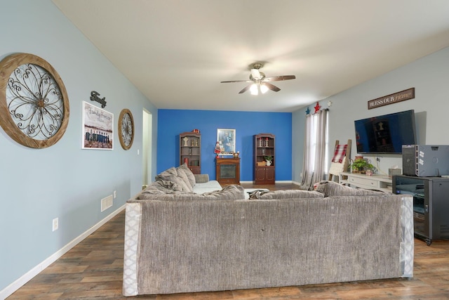 living room featuring dark wood-type flooring and ceiling fan