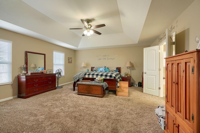 bedroom with ceiling fan, light colored carpet, and a tray ceiling