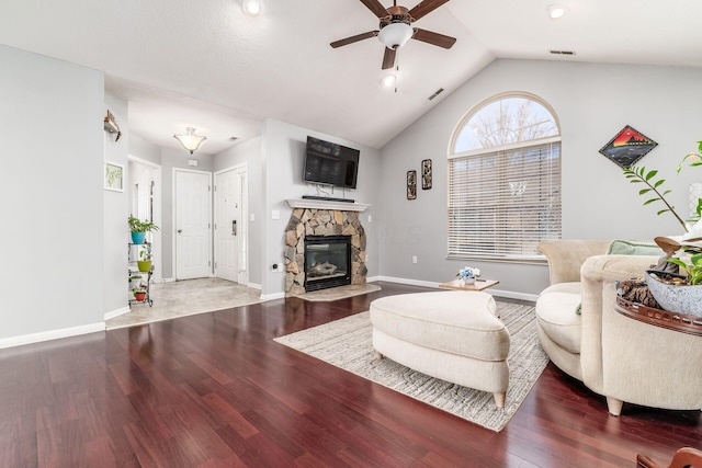 living room with a stone fireplace, hardwood / wood-style floors, lofted ceiling, and ceiling fan