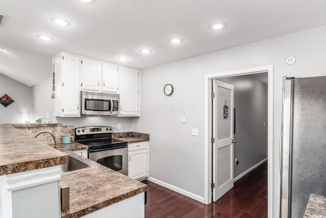 kitchen with sink, white cabinets, dark hardwood / wood-style flooring, kitchen peninsula, and stainless steel appliances