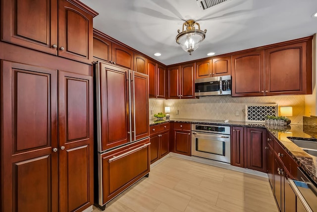 kitchen featuring tasteful backsplash, dark stone counters, and appliances with stainless steel finishes