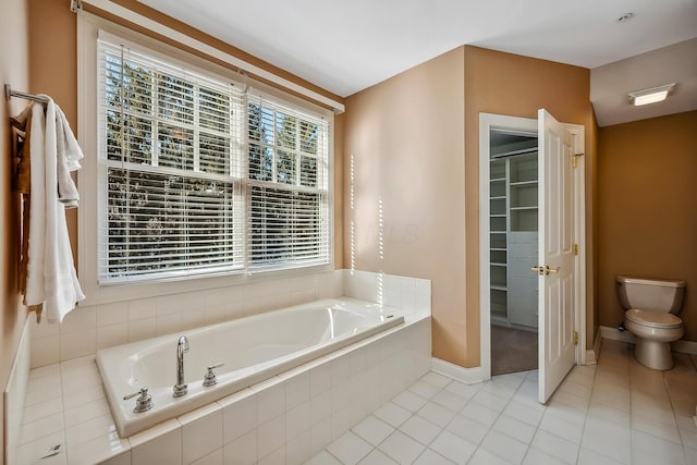 bathroom featuring toilet, tile patterned floors, and tiled bath