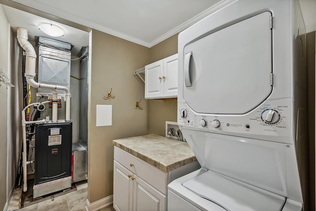 laundry area featuring cabinets, stacked washer / dryer, heating unit, and ornamental molding