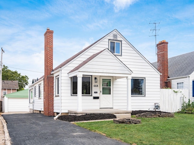 bungalow with a garage, an outdoor structure, and a front yard