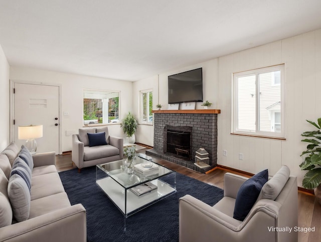 living room featuring a healthy amount of sunlight, a fireplace, and dark hardwood / wood-style flooring