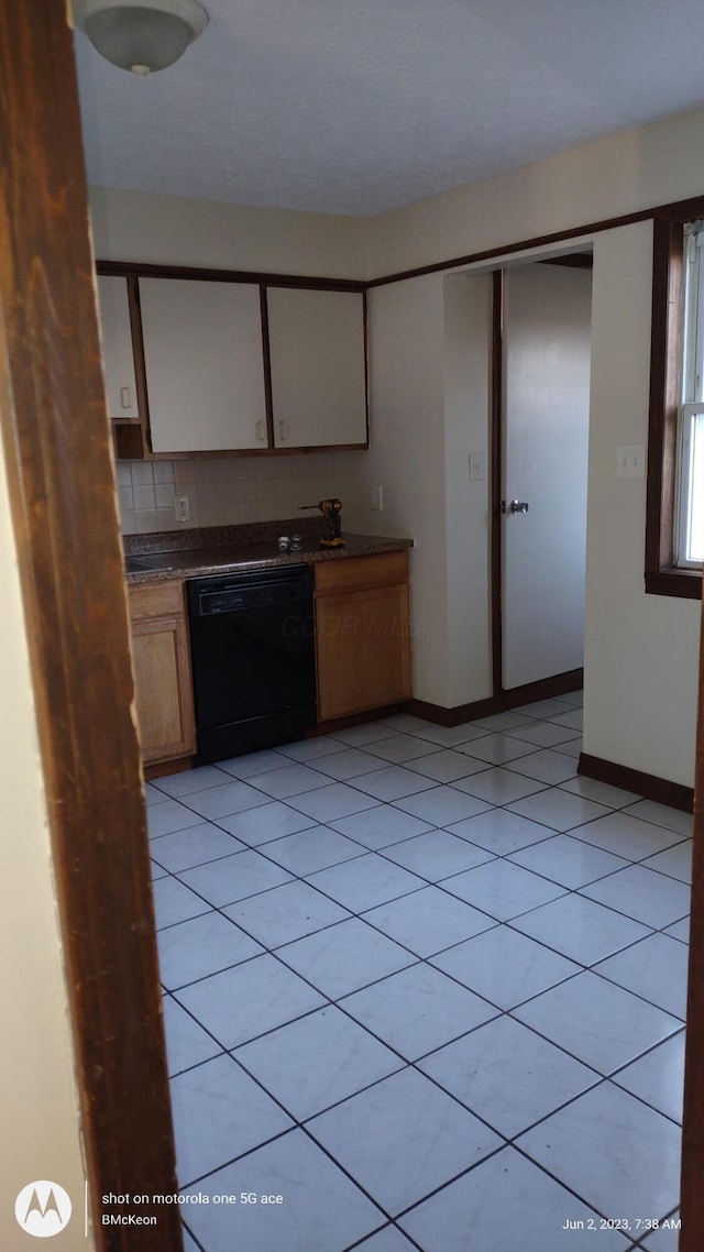 kitchen featuring tasteful backsplash, black dishwasher, and light tile patterned floors