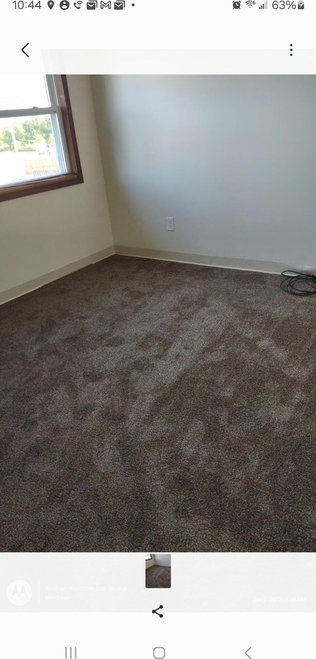 unfurnished room featuring dark carpet