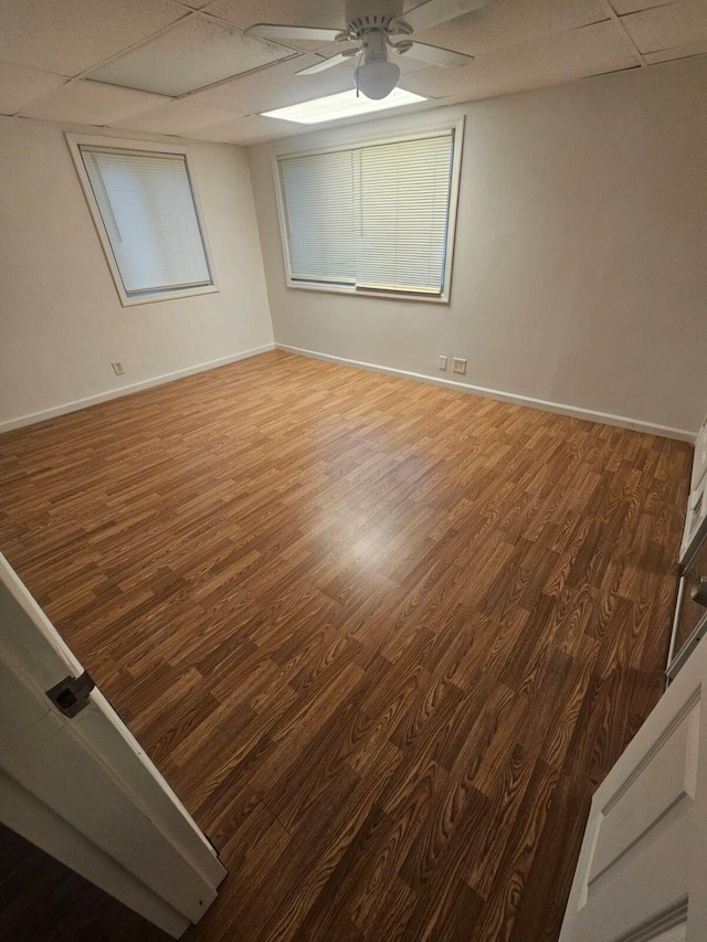 empty room with hardwood / wood-style floors, a drop ceiling, and ceiling fan