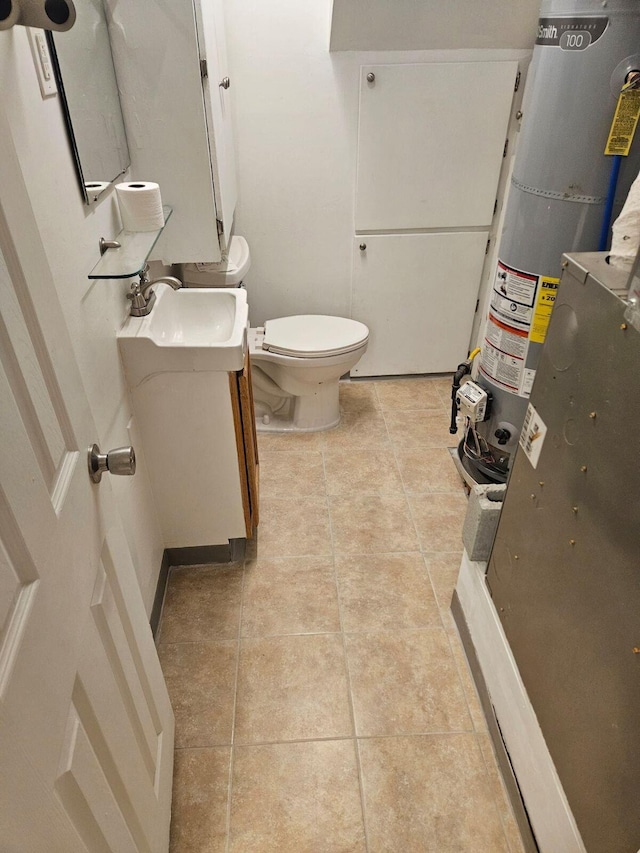 bathroom featuring vanity, toilet, tile patterned flooring, and water heater